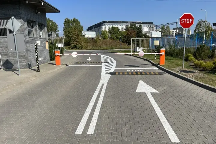 Przed wjazdem na teren hotelu Mercure widać szlabany i znaki ostrzegawcze: STOP, strzałki kierunkowe i progi zwalniające.