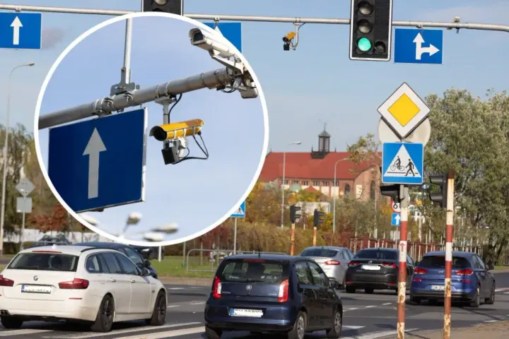Zbliżenie na kamery monitoringu przy drogowskazie z białym strzałką w górę.