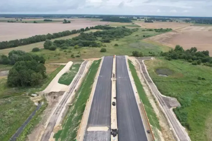Budowa drogi ekspresowej S2 Siedlce-Biała Podlaska. Nowa nawierzchnia asfaltowa w otoczeniu zieleni i pól.
