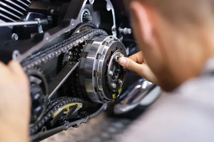 Mechanik reguluje sprzęgło, kluczowy element do nauki, jak zmieniać biegi w motocyklu 125.