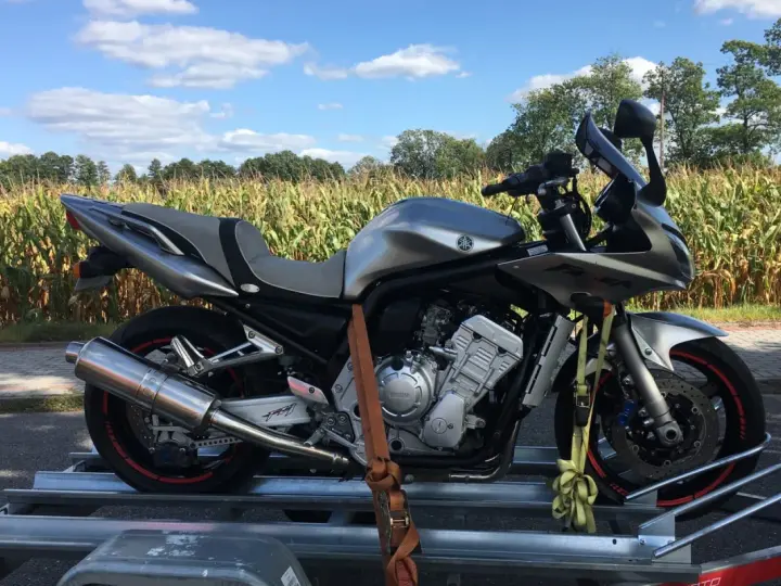 Srebrny motocykl na przyczepce, gotowy do transportu. Idealne tanie motocykle z Niemiec dla każdego fana dwóch kółek.