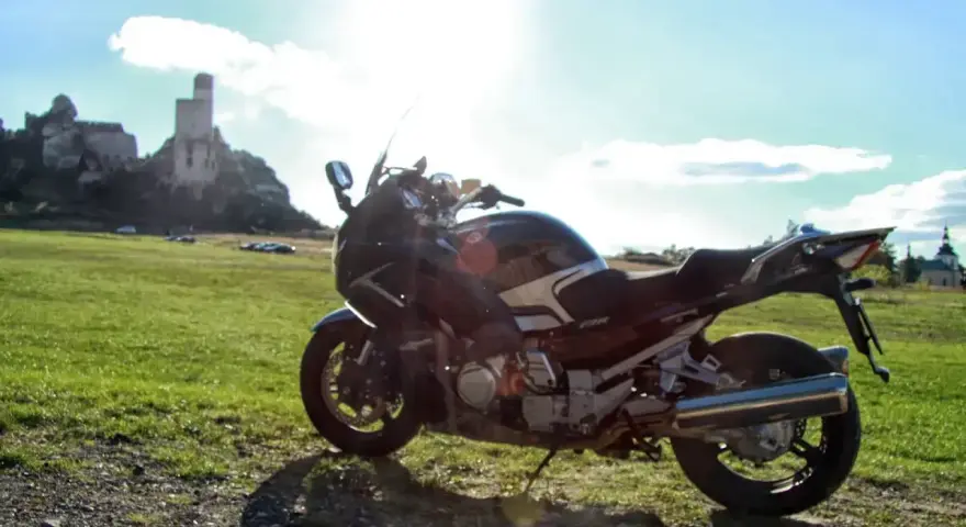 Motocykl na tle zamku w skale. Idealny kompan na podróż po Jurze Krakowsko-Częstochowskiej.