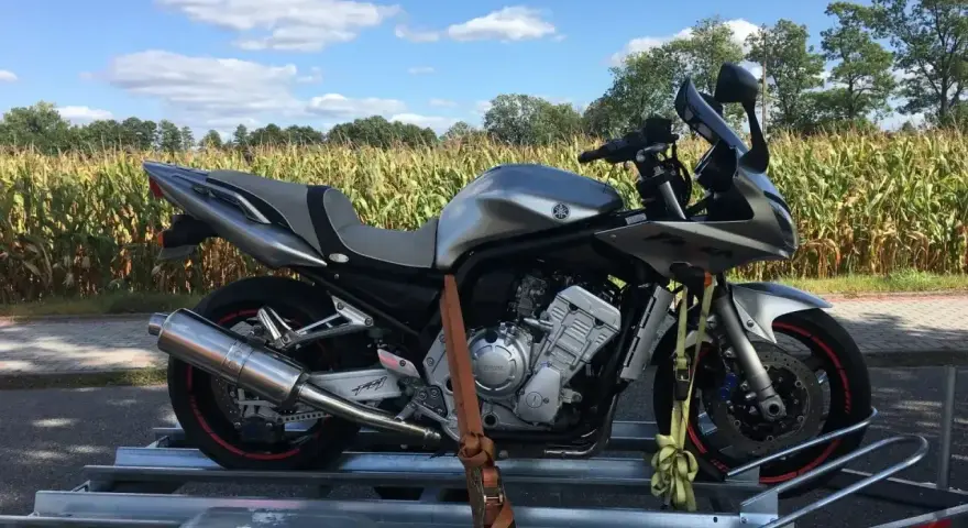 Srebrny motocykl Yamaha Fazer na przyczepce. Zastanawiasz się, ile kosztuje motocykl? Ten model to świetna opcja.