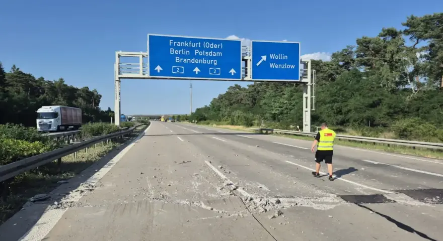 Uszkodzona autostrada A2 Niemcy. Na drodze leżą gruzy, a pracownik w kamizelce odblaskowej ogląda zniszczenia.