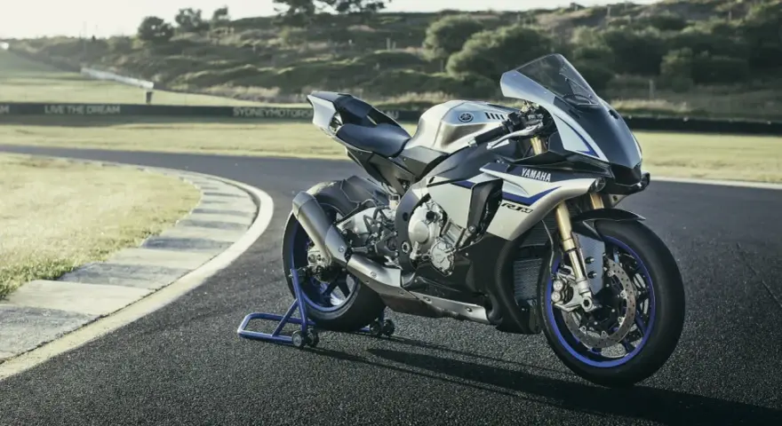 Srebrno-niebieski motocykl Yamaha R1M na torze wyścigowym, gotowy do jazdy.