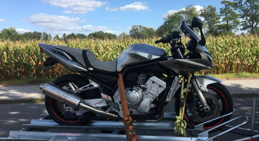 Srebrny motocykl na przyczepce, gotowy do transportu. Idealne tanie motocykle z Niemiec dla każdego fana dwóch kółek.