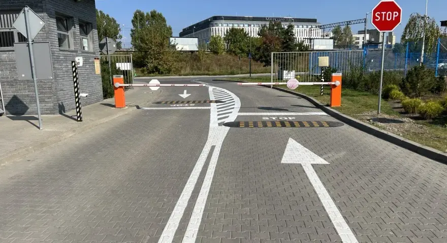 Przed wjazdem na teren hotelu Mercure widać szlabany i znaki ostrzegawcze: STOP, strzałki kierunkowe i progi zwalniające.