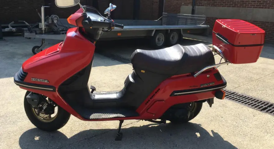 Czerwony skuter Honda Spacy 250 z kufrem, gotowy do podróży.