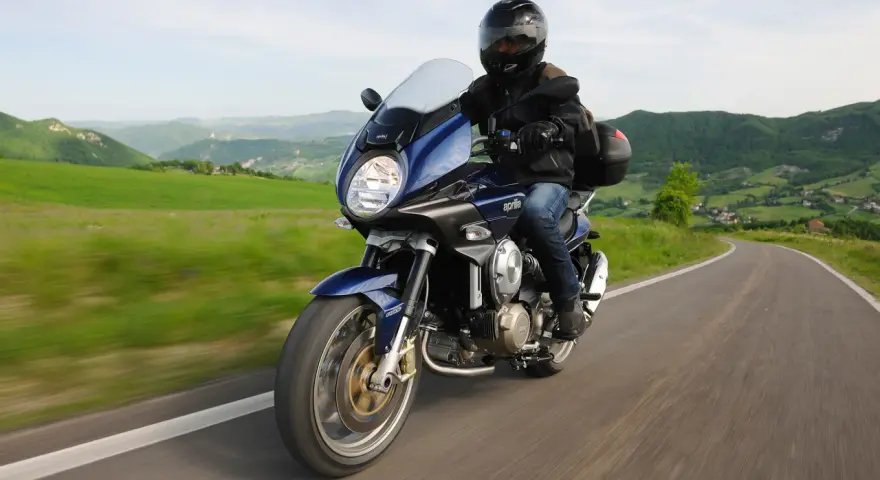 Motocykle szosowo turystyczne przemierzają malownicze, zielone wzgórza.