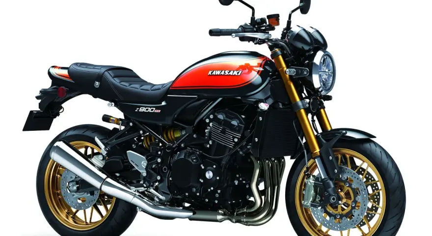 Stylowy czarny motocykl Kawasaki Z900RS z pomarańczowo-żółtym malowaniem na baku i złotymi felgami.