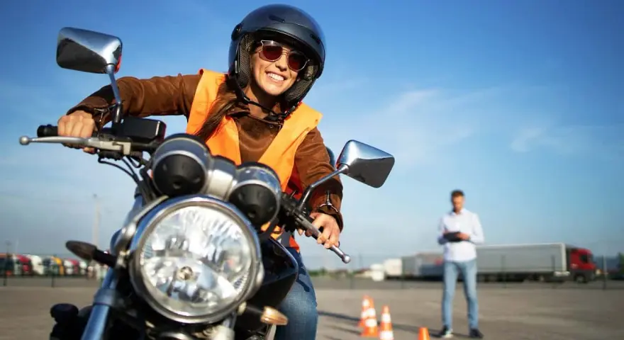 Uśmiechnięta kursantka na motorze, gotowa na egzamin. Zastanawiasz się, jakie prawo jazdy na motor 1000? To kategoria A.