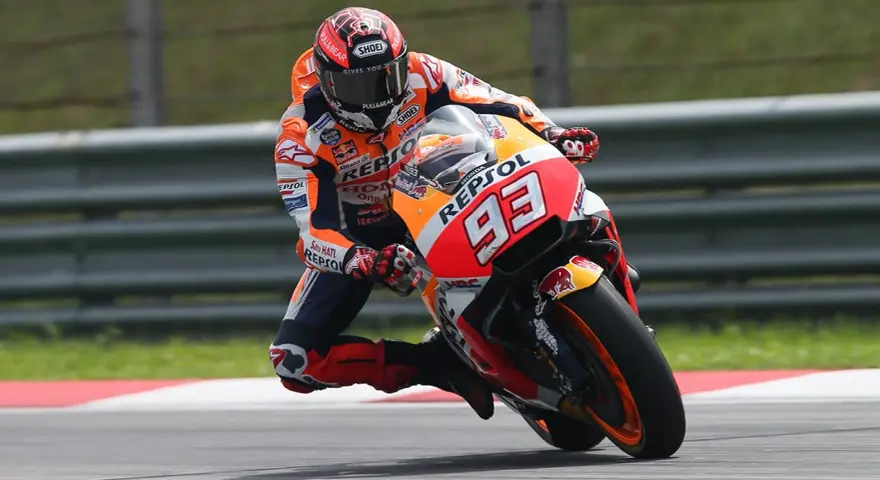 Motocyklista w kombinezonie Repsol Honda z numerem 93 wykonuje ostry zakręt, stosując technikę przeciwskrętu.