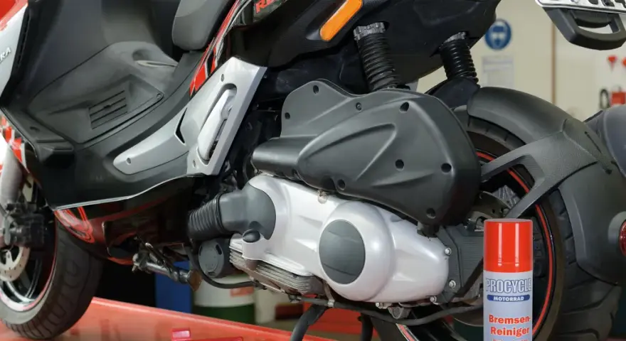 Skuter Gilera z widocznym silnikiem 4t. Może to być przyczyna, dla której po dodaniu gazu silnik się dusi. Obok stoi spray do czyszczenia hamulców.