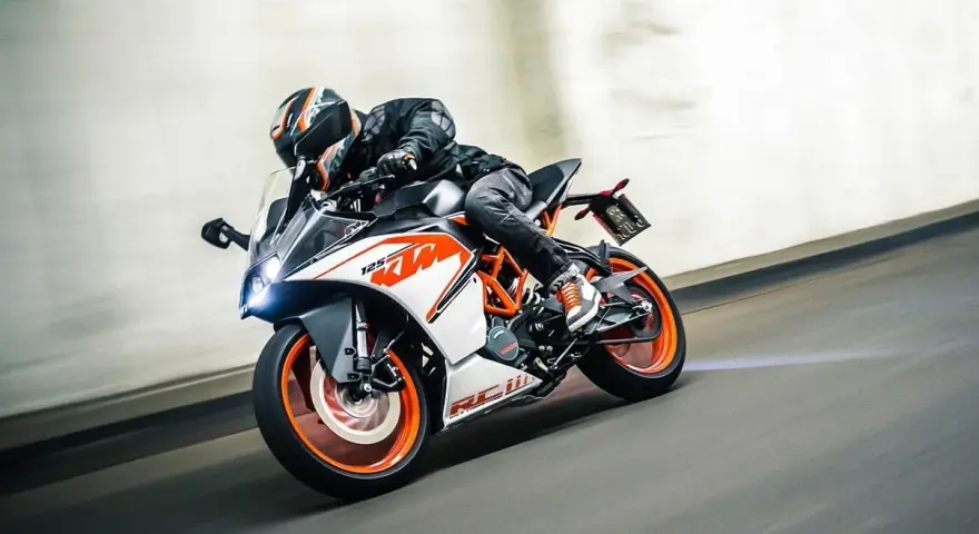 Motocyklista w kasku śmiga na KTM RC 125, osiągając maksymalną prędkość na torze.