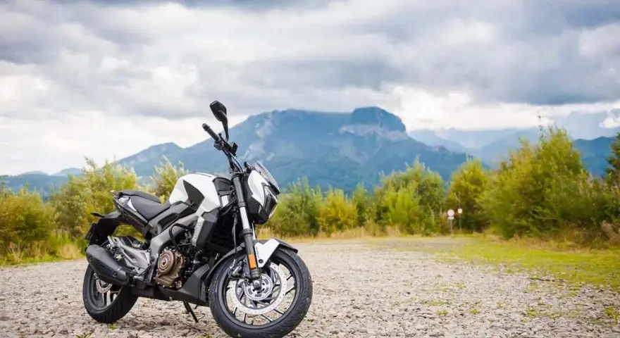 Biało-czarny Bajaj Dominar 400 na tle gór i chmur. Gotowy na przygodę w dziczy.