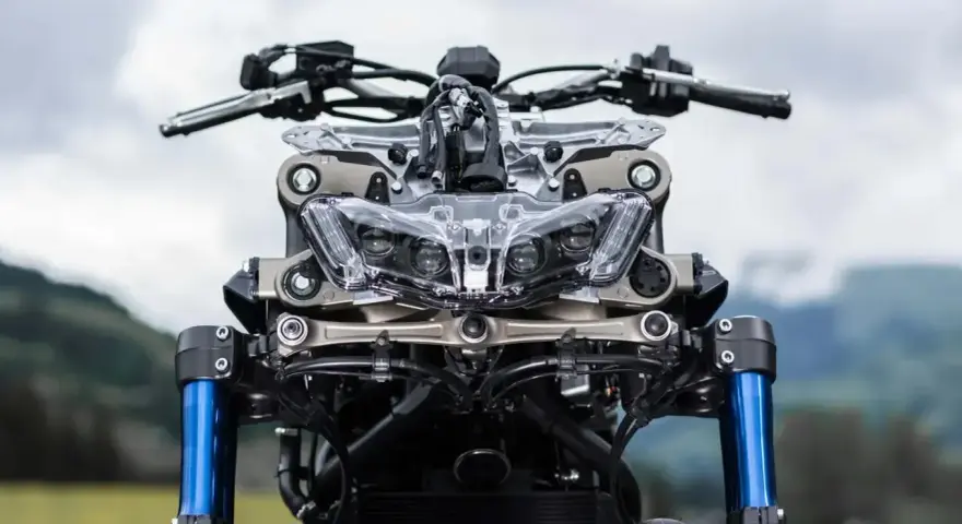 Przód motocykla Yamaha Niken GT z niebieskimi lagami i charakterystycznym, wielopunktowym reflektorem.