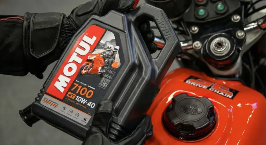 Rękawice motocyklisty trzymają olej Motul 7100 10W-40. Pytanie: co ile wymieniać olej w motocyklu?
