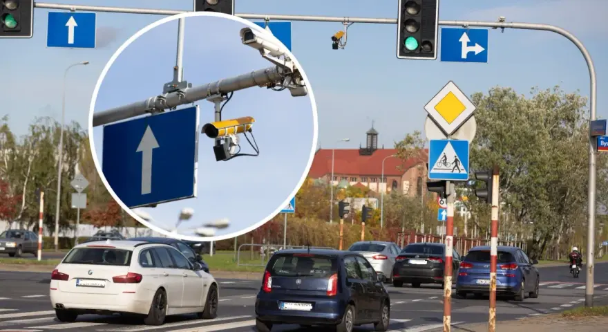 Zbliżenie na kamery monitoringu przy drogowskazie z białym strzałką w górę.