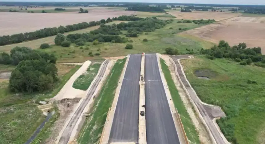 Budowa drogi ekspresowej S2 Siedlce-Biała Podlaska. Nowa nawierzchnia asfaltowa w otoczeniu zieleni i pól.