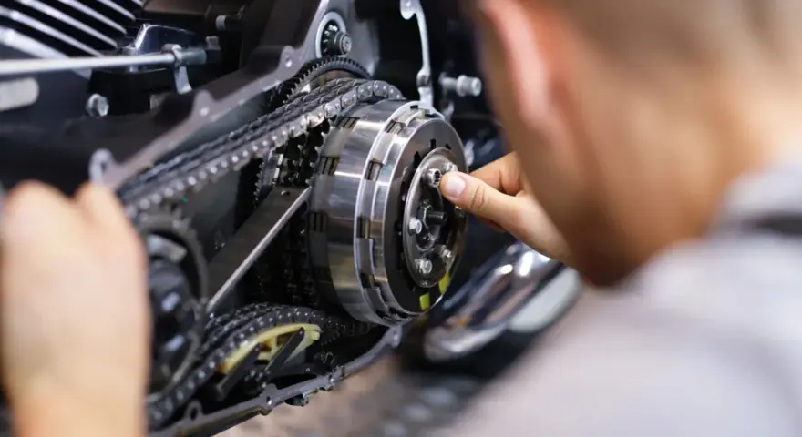 Mechanik reguluje sprzęgło, kluczowy element do nauki, jak zmieniać biegi w motocyklu 125.