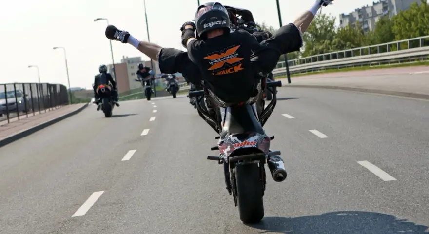 Motocyklista wykonuje jazdę na jednym kole, rozkrokiem. Ryzykowne wyczyny mogą skończyć się mandatem.