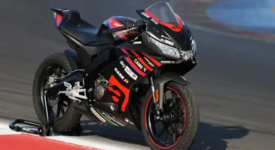 Czarna Aprilia RS 125 2T V-Max na torze wyścigowym, gotowa do osiągnięcia maksymalnej prędkości.