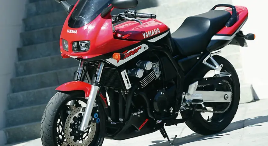 Czerwony motocykl Yamaha Fazer z czarnym siedzeniem i detalami, gotowy do jazdy.