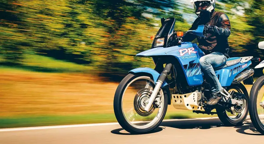 Motocyklista na niebieskim Suzuki DR 800 Big pędzi po drodze. Poznaj suzuki dr 800 big dane techniczne i poczuj wolność.