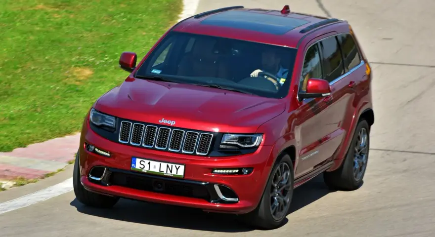 Czerwony Jeep Grand Cherokee na torze. Zastanawiasz się, ile kosztuje personalizowana rejestracja, gdy widzisz tablicę S1 LNY?