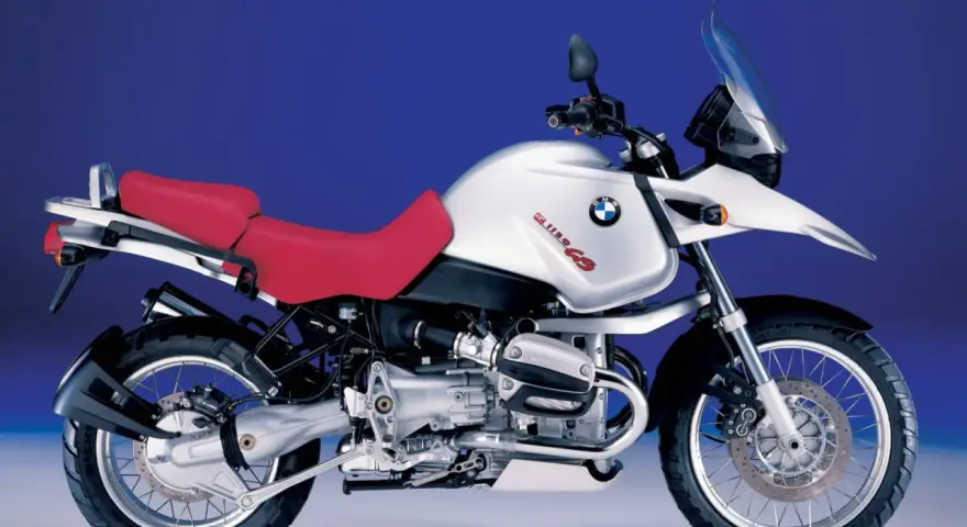 Srebrny motocykl BMW R 1150 GS z czerwoną kanapą, gotowy na przygodę.