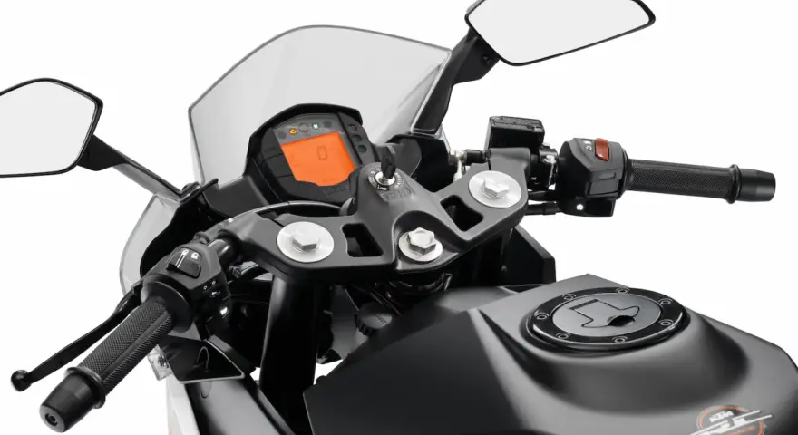 Widok na kierownicę motocykla KTM z cyfrowym wyświetlaczem, lusterkami i uchwytem.