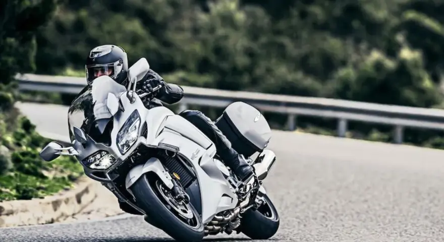 Motocyklista w kasku pochyla się na białym motocyklu Yamaha FJR 1300, pokonując zakręt. Dane techniczne tego modelu są imponujące.