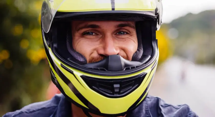 Uśmiechnięty mężczyzna w żółtym kasku motocyklowym.
