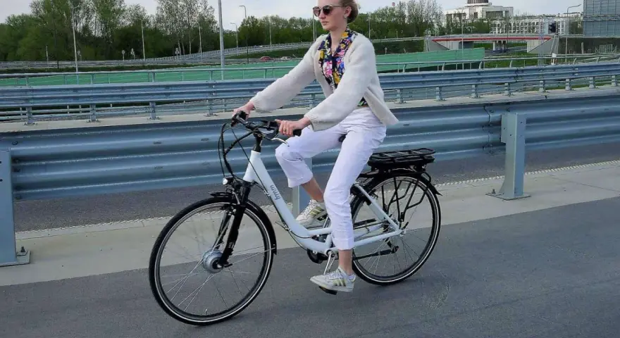 Młoda kobieta na rowerze elektrycznym, zastanawia się, czy na rower elektryczny trzeba mieć prawo jazdy.