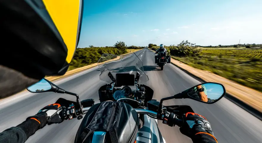 Przełęcz Salmopolska widziana z perspektywy motocyklisty. Droga wijąca się pośród zielonych pól, błękitne niebo i inny motocykl przed nami.