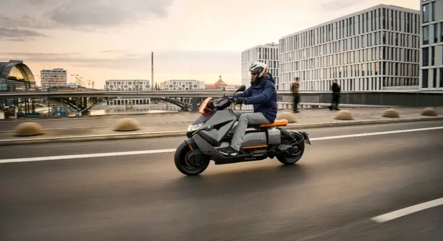 Mężczyzna w kasku jedzie na skuterze BMW CE 04 po mieście.