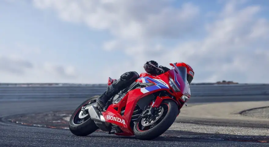 Czerwony motocykl Honda CBR650R z kierowcą pochylonym na zakręcie toru wyścigowego.