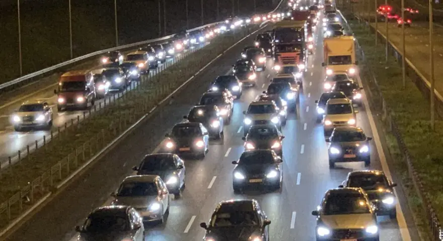 Nocny korek na drodze S8. Długi sznur samochodów i ciężarówek z zapalonymi światłami tworzy świetlisty tunel.