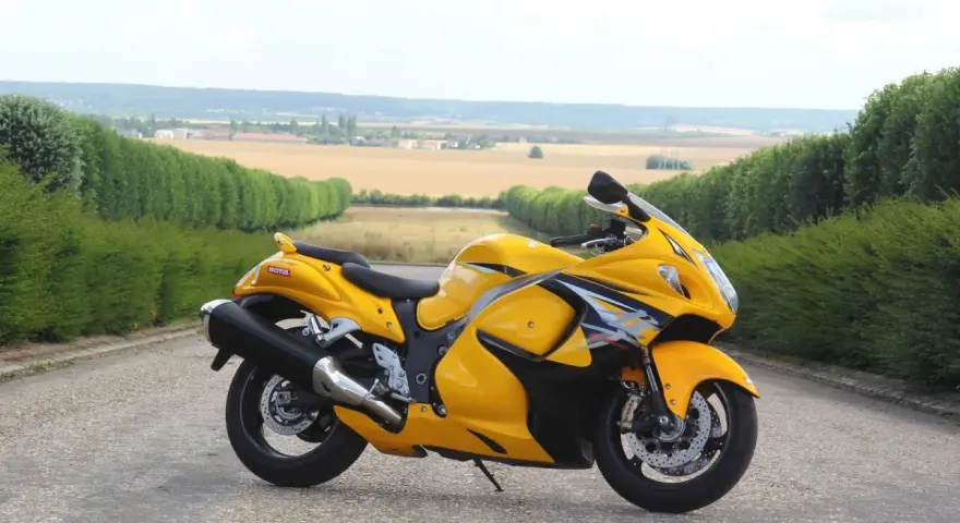 Żółty Suzuki Hayabusa na tle pól i zielonych żywopłotów. Sprawdź aktualną suzuki hayabusa cena!