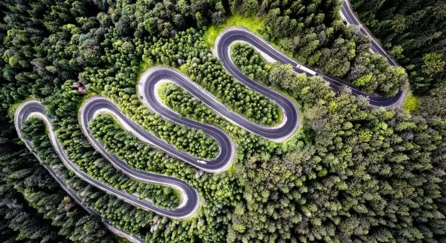 Wężykująca droga przez gęsty las, idealna na jednodniowy wypad motocyklowy.