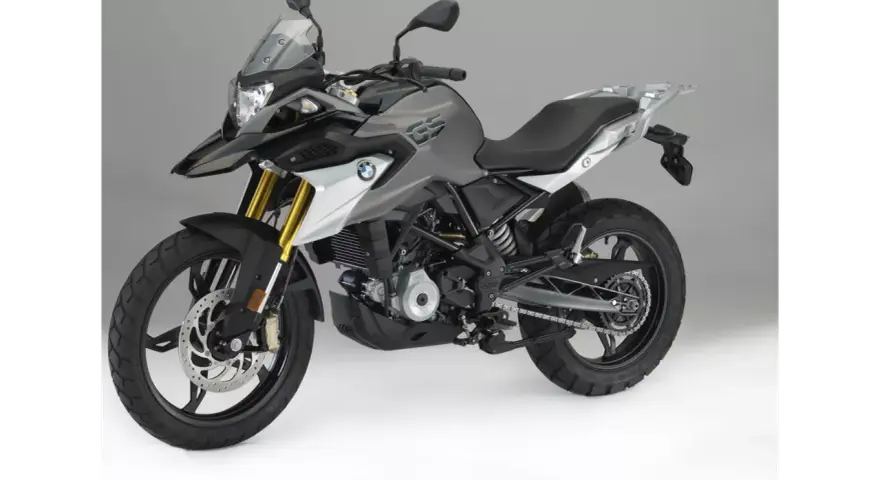 Szary motocykl BMW 310 GS z czarnym siedzeniem i złotymi amortyzatorami, gotowy na przygodę.