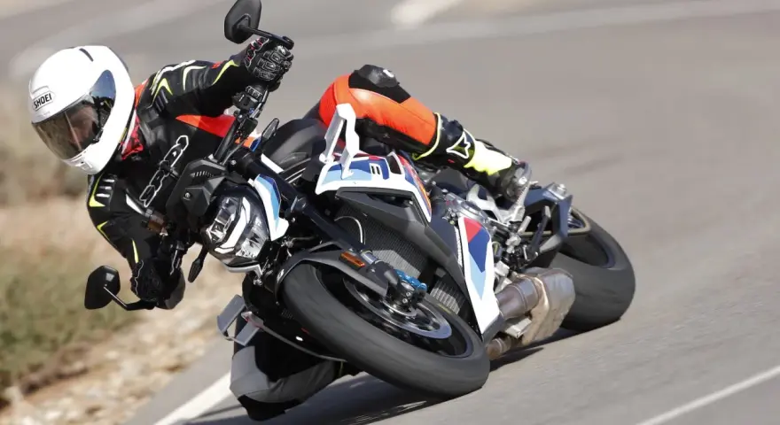 Motocyklista w kombinezonie i kasku pochyla się na zakręcie na sportowym motocyklu BMW. DTC BMW zapewnia kontrolę.