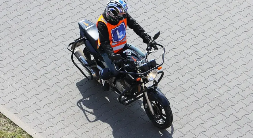 Motocyklista w kamizelce z literą "L" (kategoria A2) na placu manewrowym.