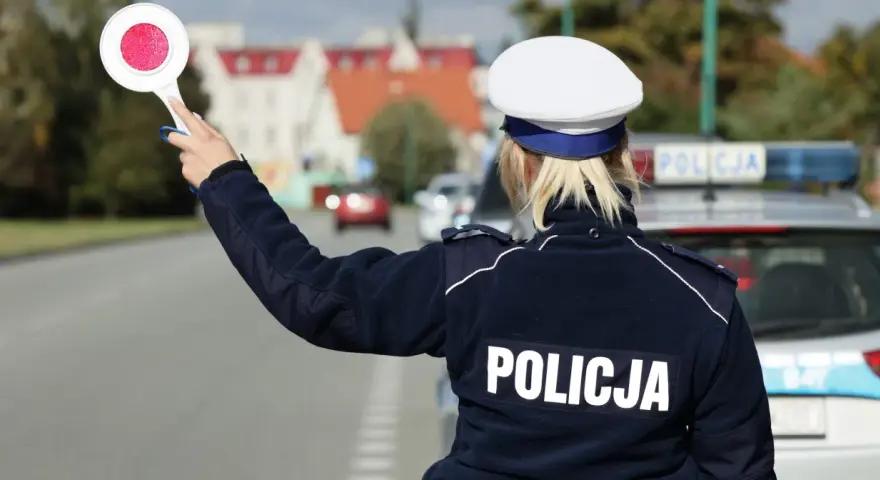 Policjantka z tarczą zatrzymuje ruch. Kierowca, który już raz dostał mandat, musi uważać, by nie popełnić kolejnego wykroczenia.