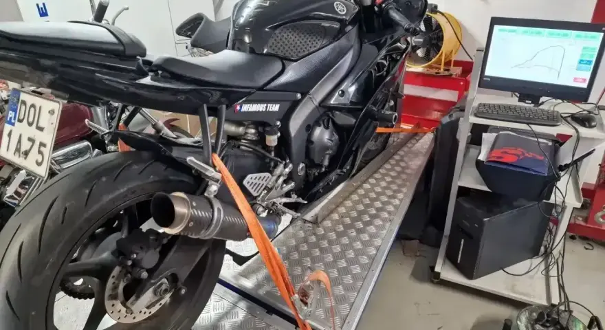Czarny motocykl na hamowni, przygotowany do testów. Pomiar mocy i momentu obrotowego, czyli blokowanie motocykla na A2, to klucz do optymalizacji osiągów.