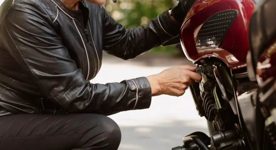 Kobieta w skórzanej kurtce sprawdza regulator napięcia w motocyklu.