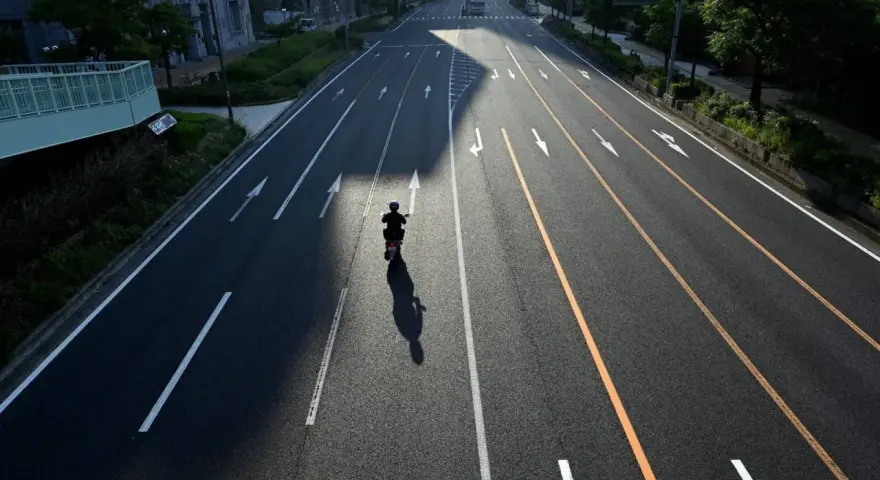 Samotny motocyklista na pustej drodze, cień rzuca się na asfalt. Zastanawia się, jak wyrejestrować skuter.