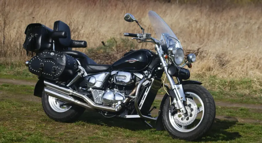 Czarny Suzuki Marauder z sakwami i szybą, gotowy na podróż przez jesienne krajobrazy.