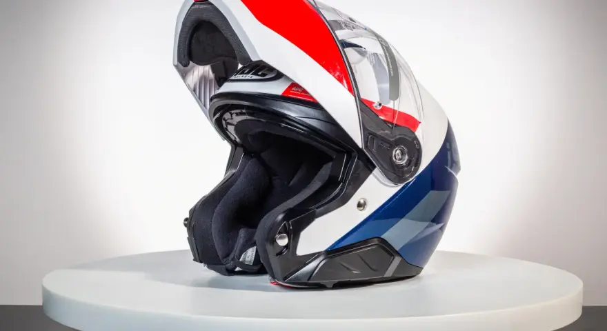 Kask motocyklowy z podniesioną szczęką, w kolorach białym, czerwonym i niebieskim, na białym tle.