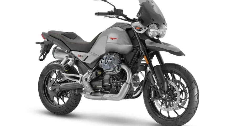 Srebrny motocykl Moto Guzzi V85 TT z charakterystycznym silnikiem V-twin, gotowy na przygodę.